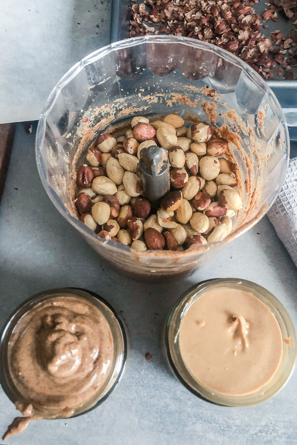 Hazelnuts in food processor and two jars of nut butter
